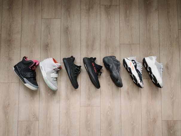 A diverse collection of footwear displayed on a wooden surface, featuring sneakers, sandals, and boots.