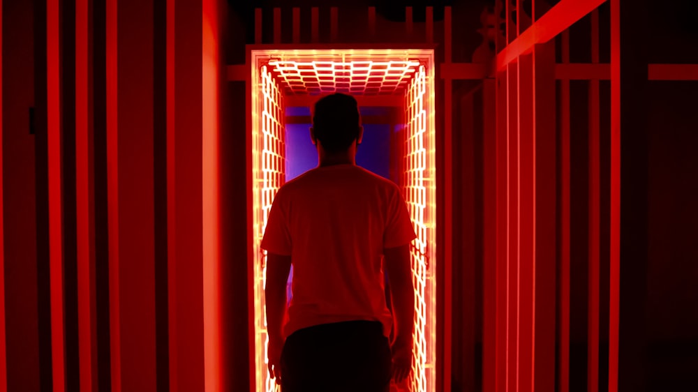 man in white crew neck t-shirt standing in front of red window curtain