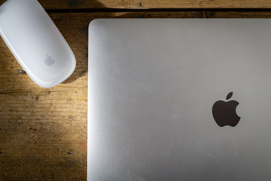 silver macbook on brown wooden table,