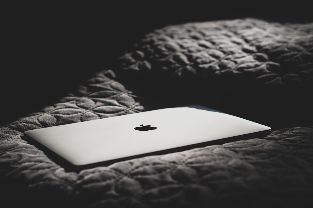 silver macbook on black and brown textile