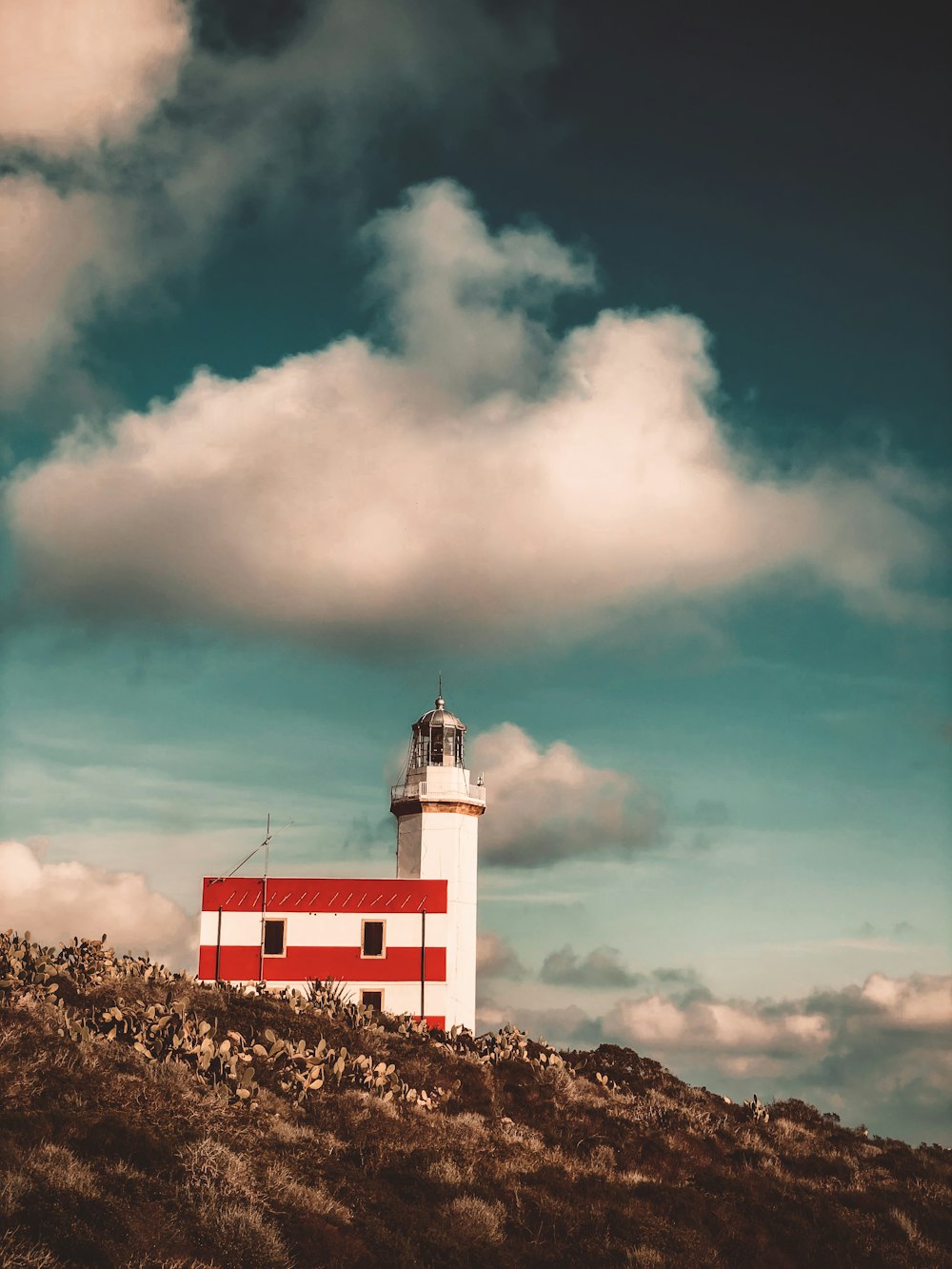 farol de concreto branco e vermelho sob o céu azul