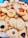 A variety of homemade cookies are arranged together. They include different shapes such as stars and flowers, with textures that appear soft and crumbly. Some cookies are topped with raisins or pieces of fruit, adding visual appeal.