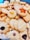 A variety of homemade cookies are arranged together. They include different shapes such as stars and flowers, with textures that appear soft and crumbly. Some cookies are topped with raisins or pieces of fruit, adding visual appeal.