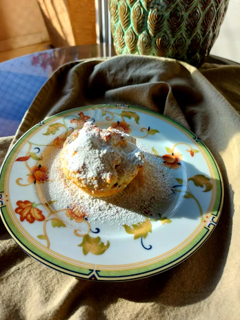 A bright turquoise ceramic plate holding a homemade pastry, set on a cozy linen tablecloth.