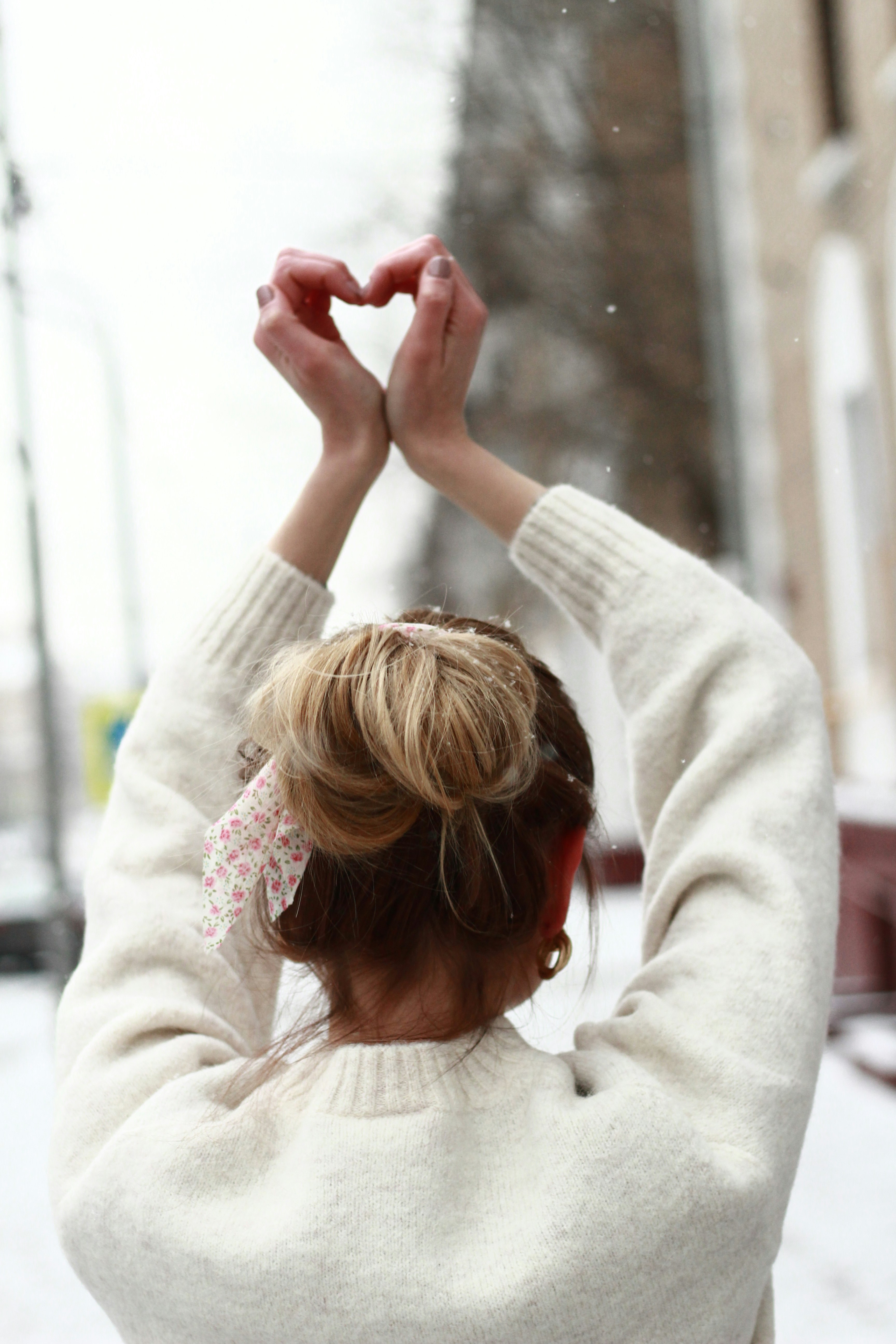 woman in white sweater holding her hair