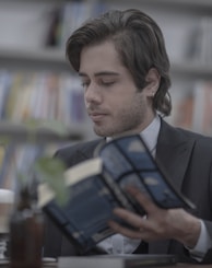 man in black suit jacket holding blue tablet computer