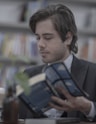 man in black suit jacket holding blue tablet computer