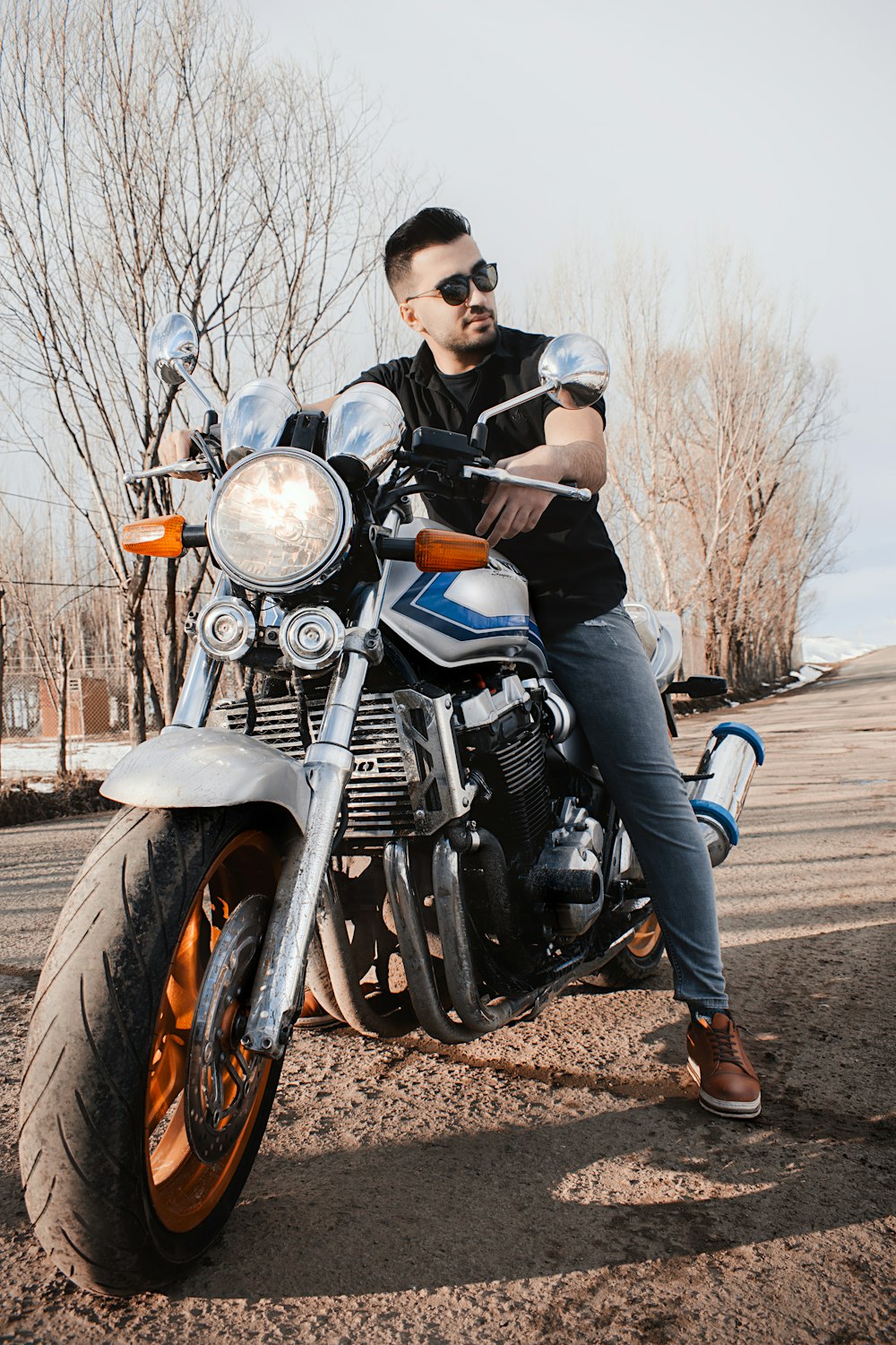 man in black jacket and blue denim jeans riding black cruiser motorcycle