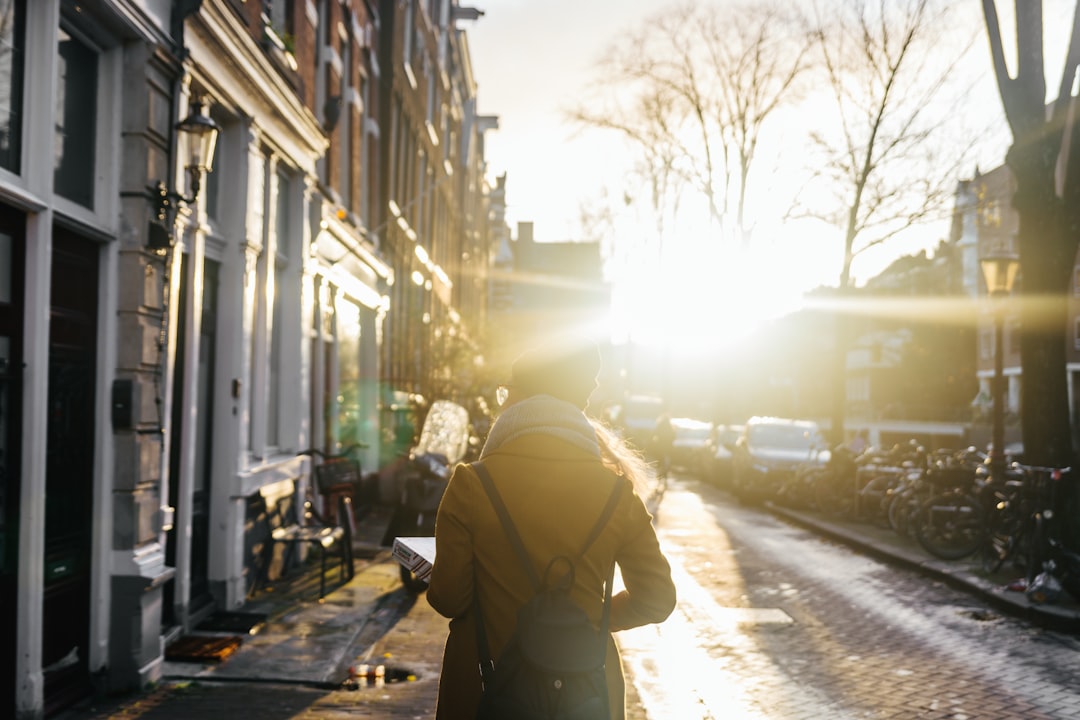 man in brown jacket standing on sidewalk during daytime