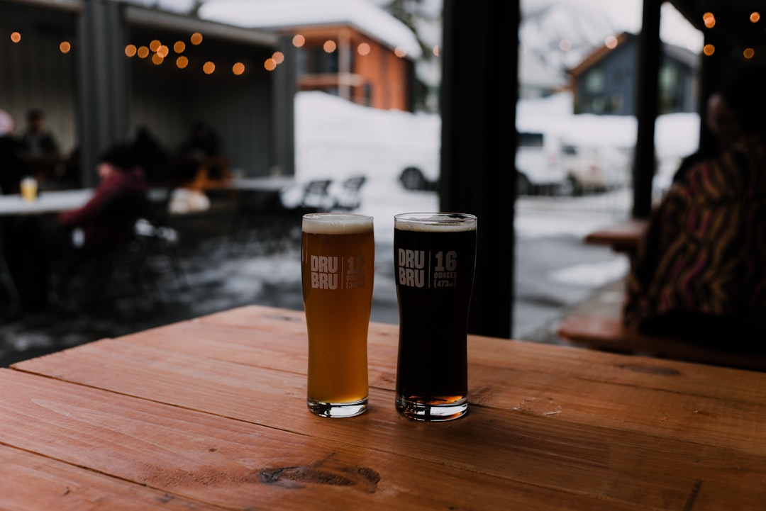 clear drinking glass with beer on brown wooden table