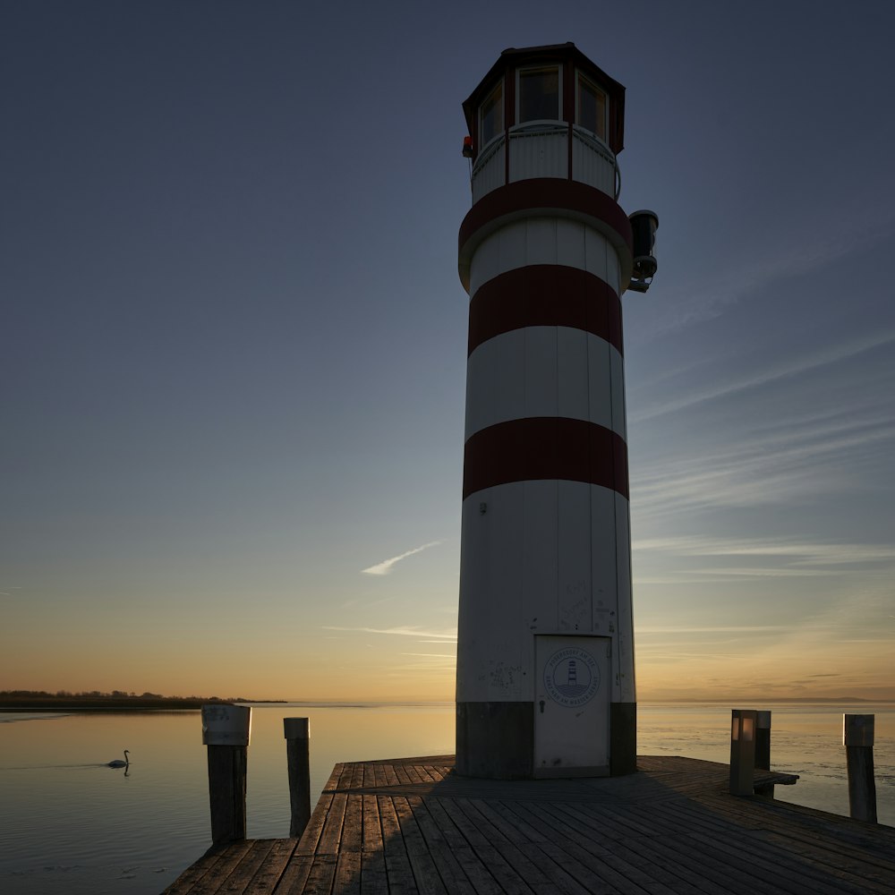 white and red lighthouse near body of water during daytime