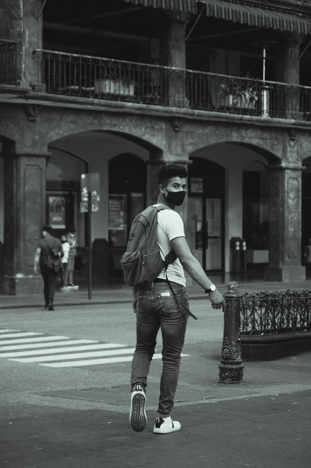 grayscale photo of woman in white shirt and denim jeans standing on pedestrian line