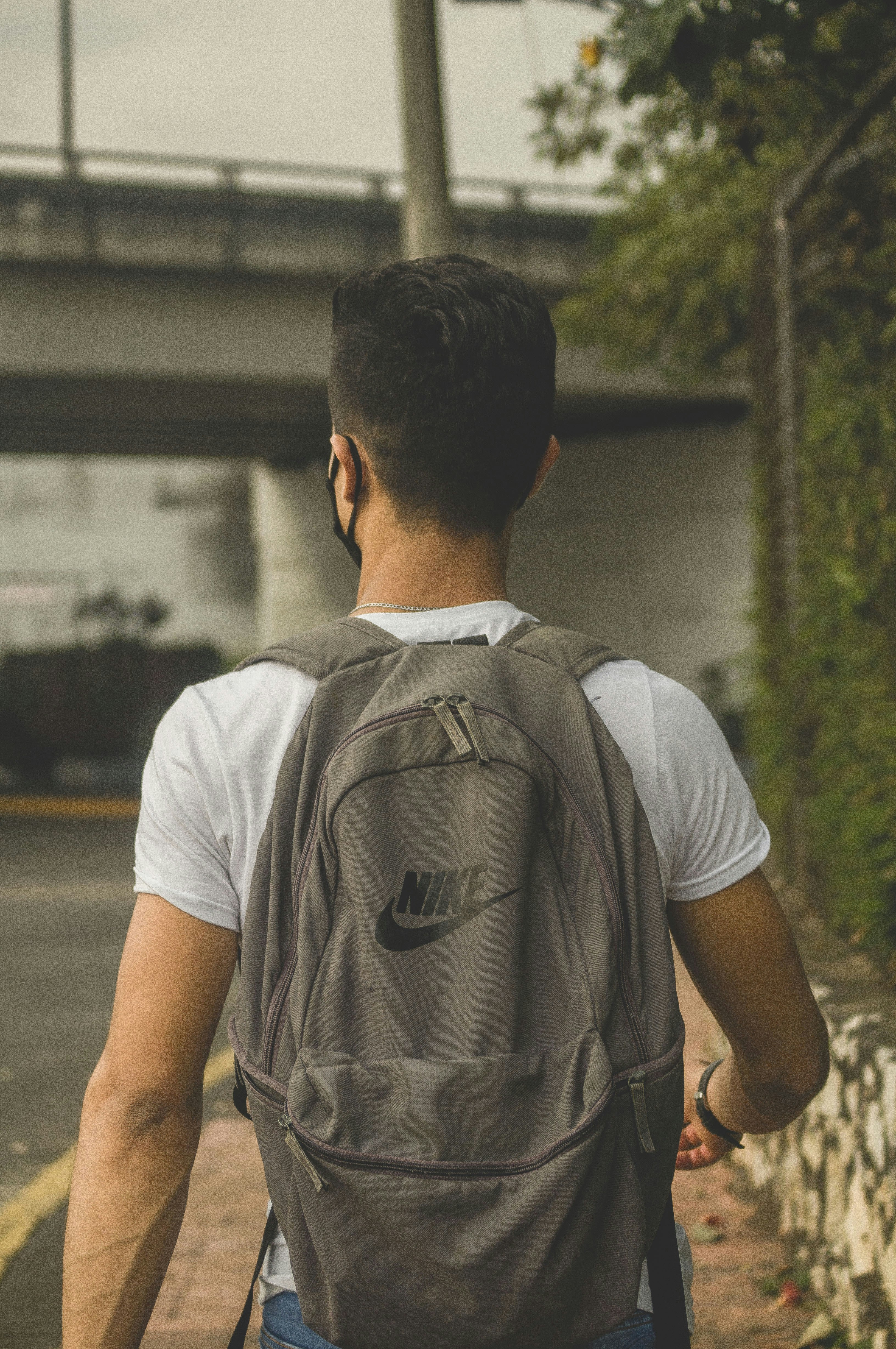Hombre con camiseta blanca de cuello redondo con mochila marrón