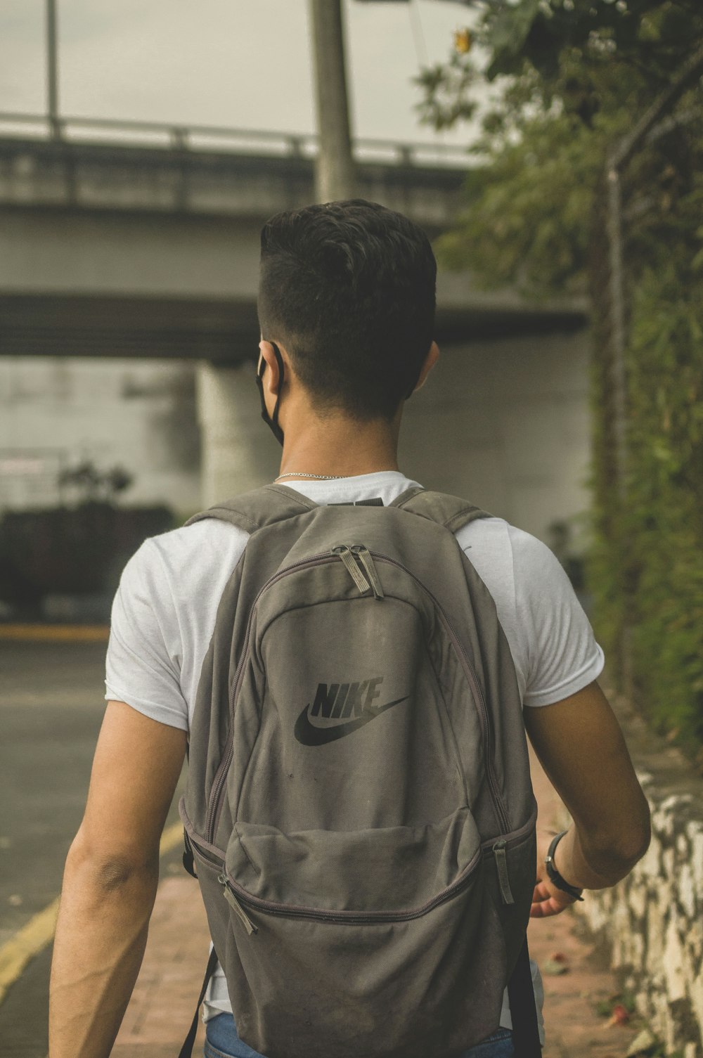 man in white crew neck t-shirt with brown backpack
