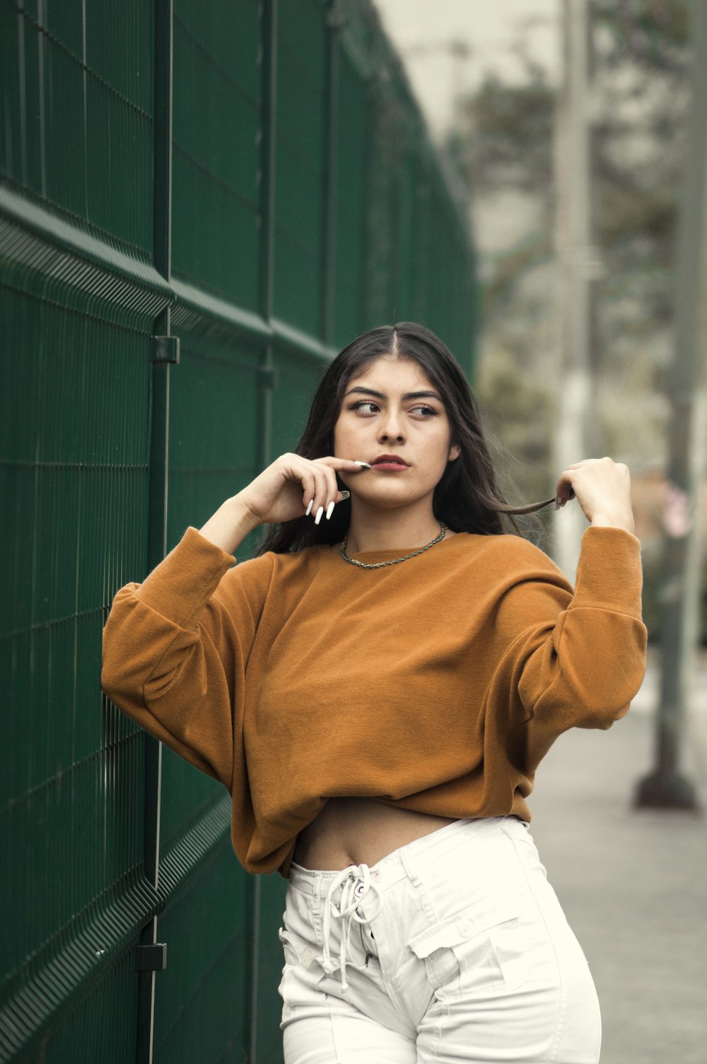 woman in brown sweater holding her face