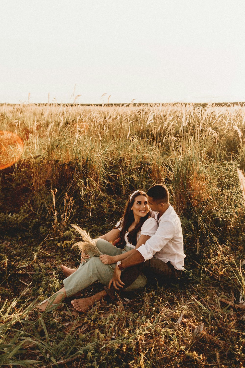 man and woman sitting on brown grass field during daytime