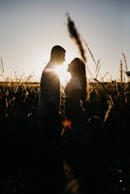 man and woman sitting on grass field during sunset