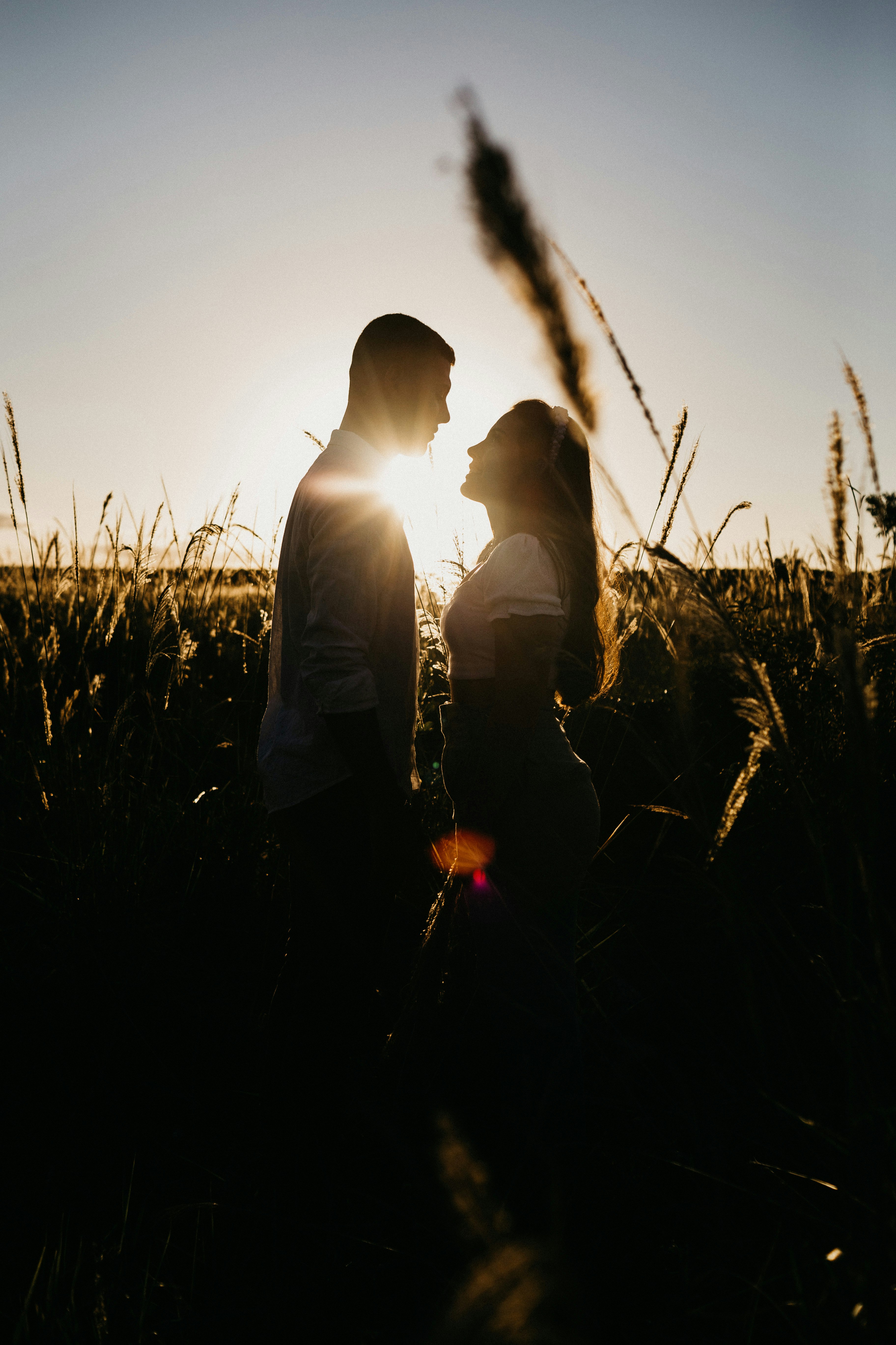 man and woman sitting on grass field during sunset
