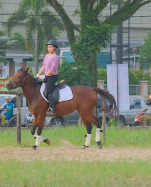 man in white shirt riding brown horse during daytime