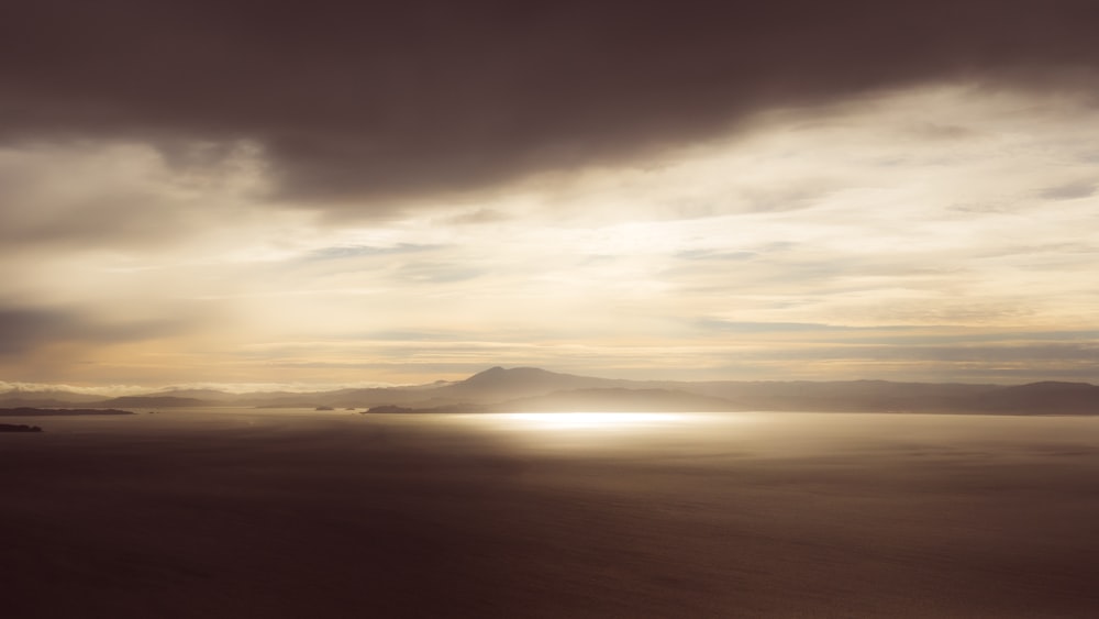 silhouette of mountain under cloudy sky during sunset