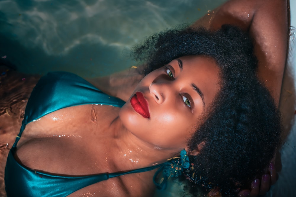 woman in blue bikini top lying on water