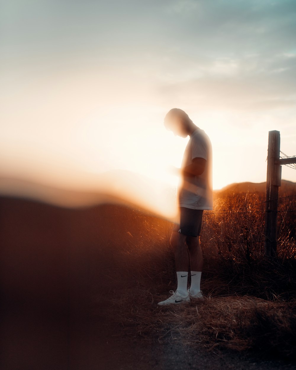 topless man in black shorts standing on green grass field during sunset