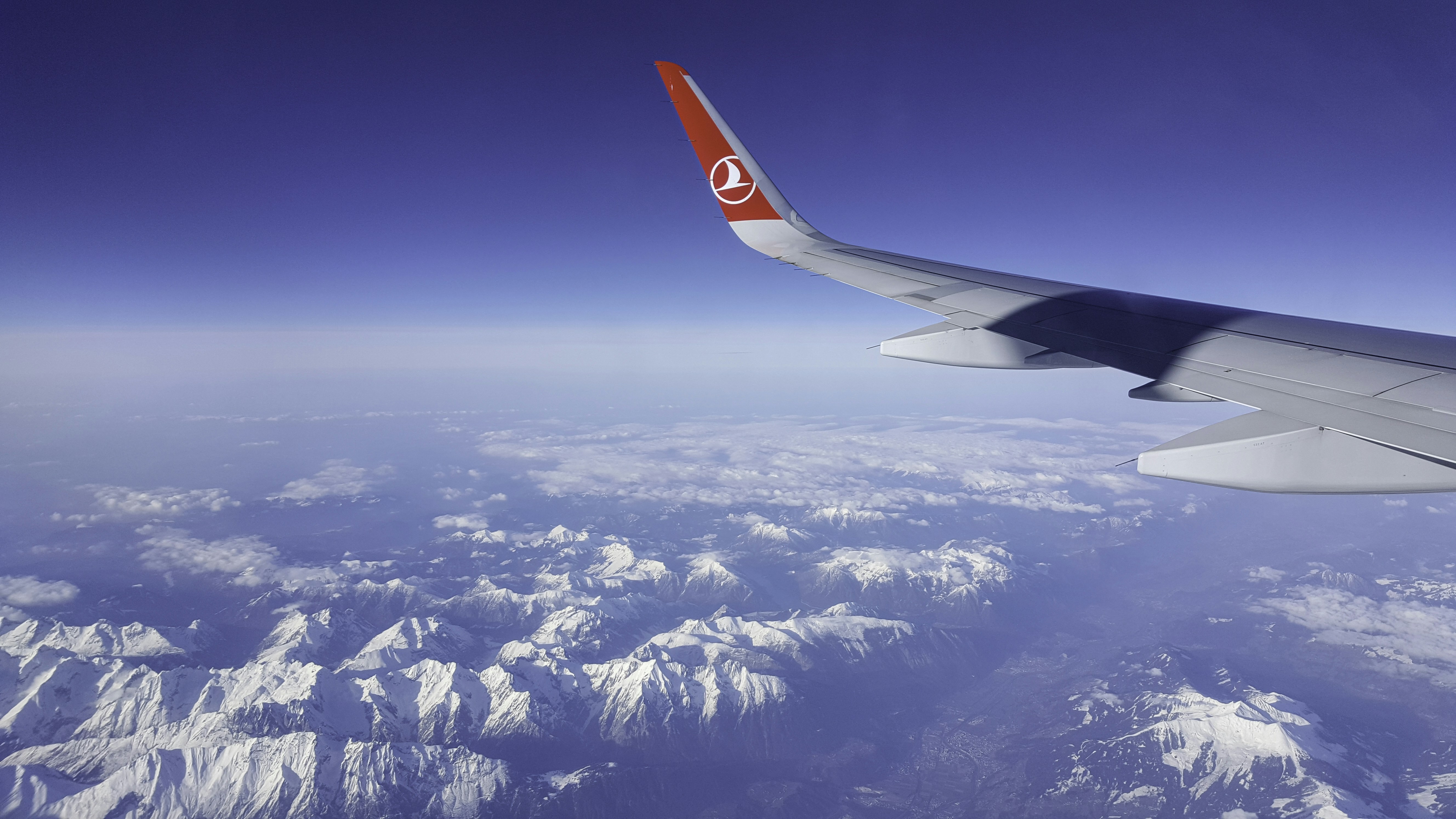 white and red airplane wing over white clouds and blue sky during daytime outstanding teams background