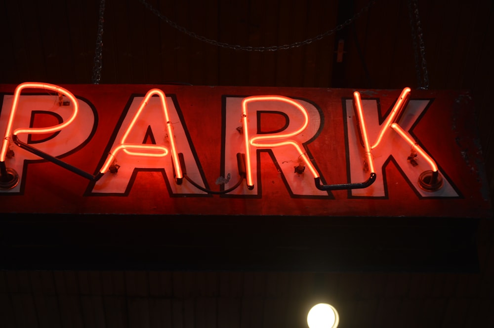 a red neon sign that says park hanging from the side of a building