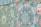 The image features a vibrant mural with intricate mandala patterns and swirling floral designs. Colors range from various shades of green to hints of purple, orange, and white. There is a bold, partially visible sign in the top right corner with contrasting red and white colors.