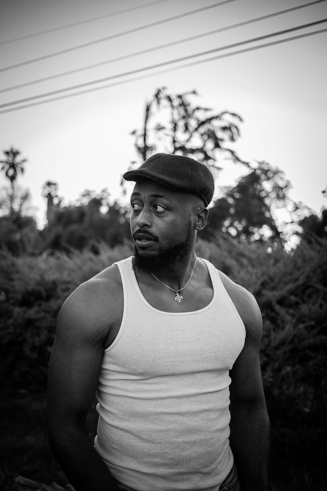 man in tank top and hat in grayscale photography