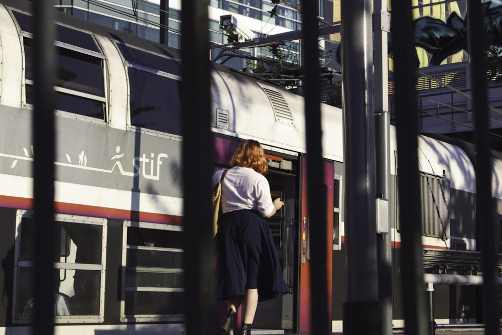 man in black jacket standing beside red and black train during daytime