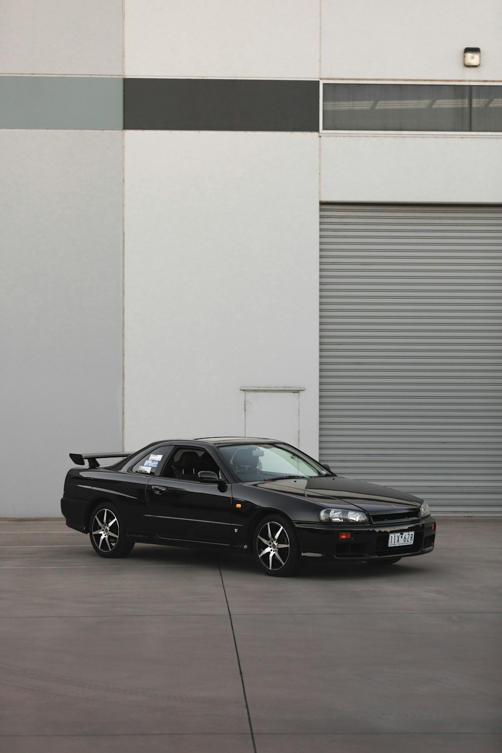 black bmw m 3 coupe parked beside white roll up door