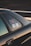 The image captures a close-up view of a car, focusing on the window area. There are stickers visible on the window, which include some text and a graphic of a vehicle. The car is black and the photo is taken at sunset, casting a warm, golden glow on the vehicle's surface.