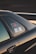 The image captures a close-up view of a car, focusing on the window area. There are stickers visible on the window, which include some text and a graphic of a vehicle. The car is black and the photo is taken at sunset, casting a warm, golden glow on the vehicle's surface.