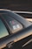 The image captures a close-up view of a car, focusing on the window area. There are stickers visible on the window, which include some text and a graphic of a vehicle. The car is black and the photo is taken at sunset, casting a warm, golden glow on the vehicle's surface.