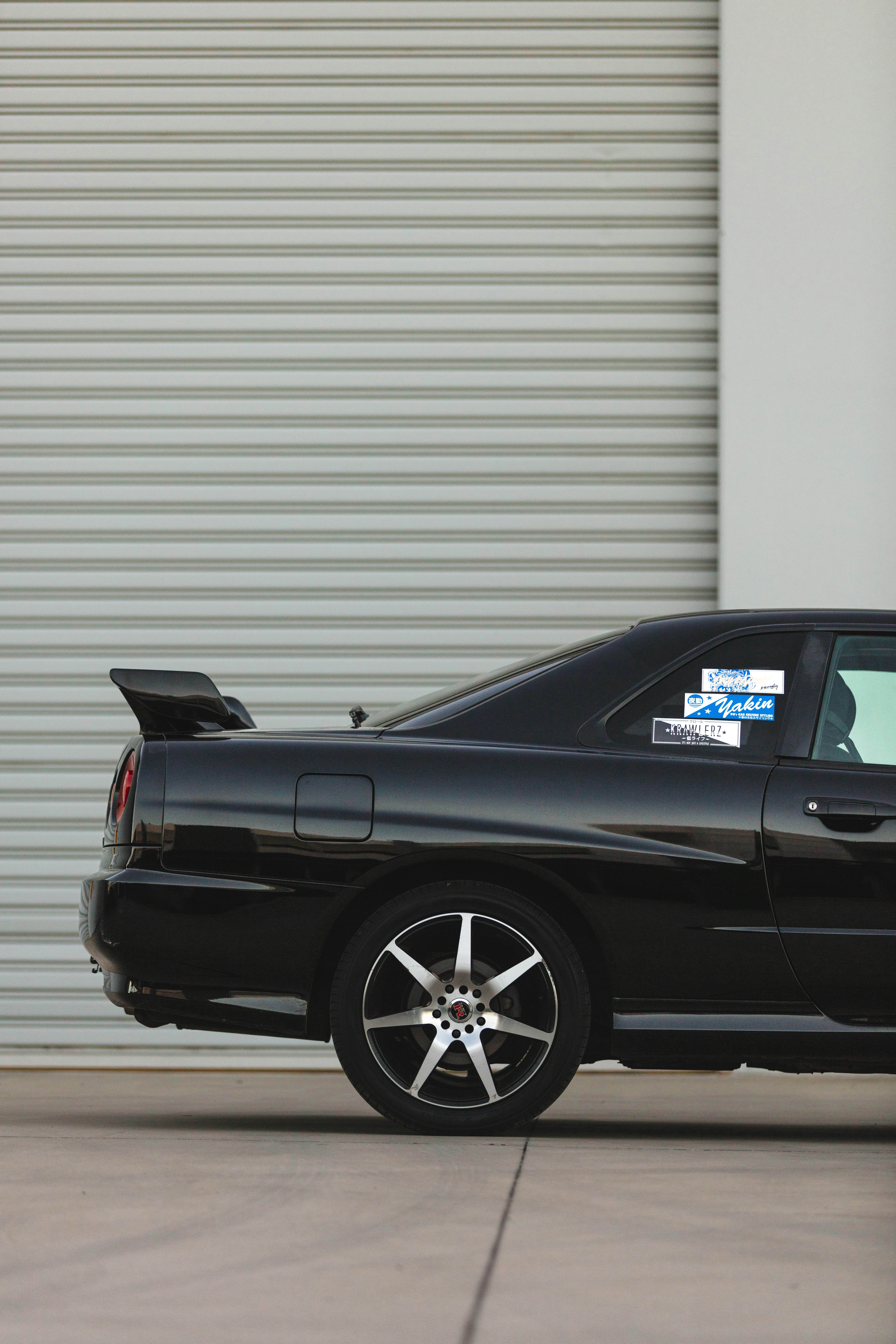 A close-up of a sleek black garage door with orange accents.