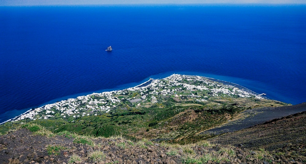 Vue aérienne de la montagne couverte d’herbe verte près de la mer bleue pendant la journée