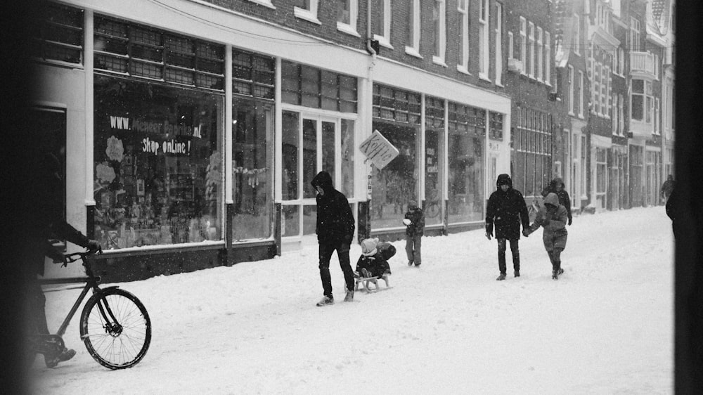 Mann in schwarzer Jacke geht mit schwarzem Hund auf schneebedecktem Boden spazieren