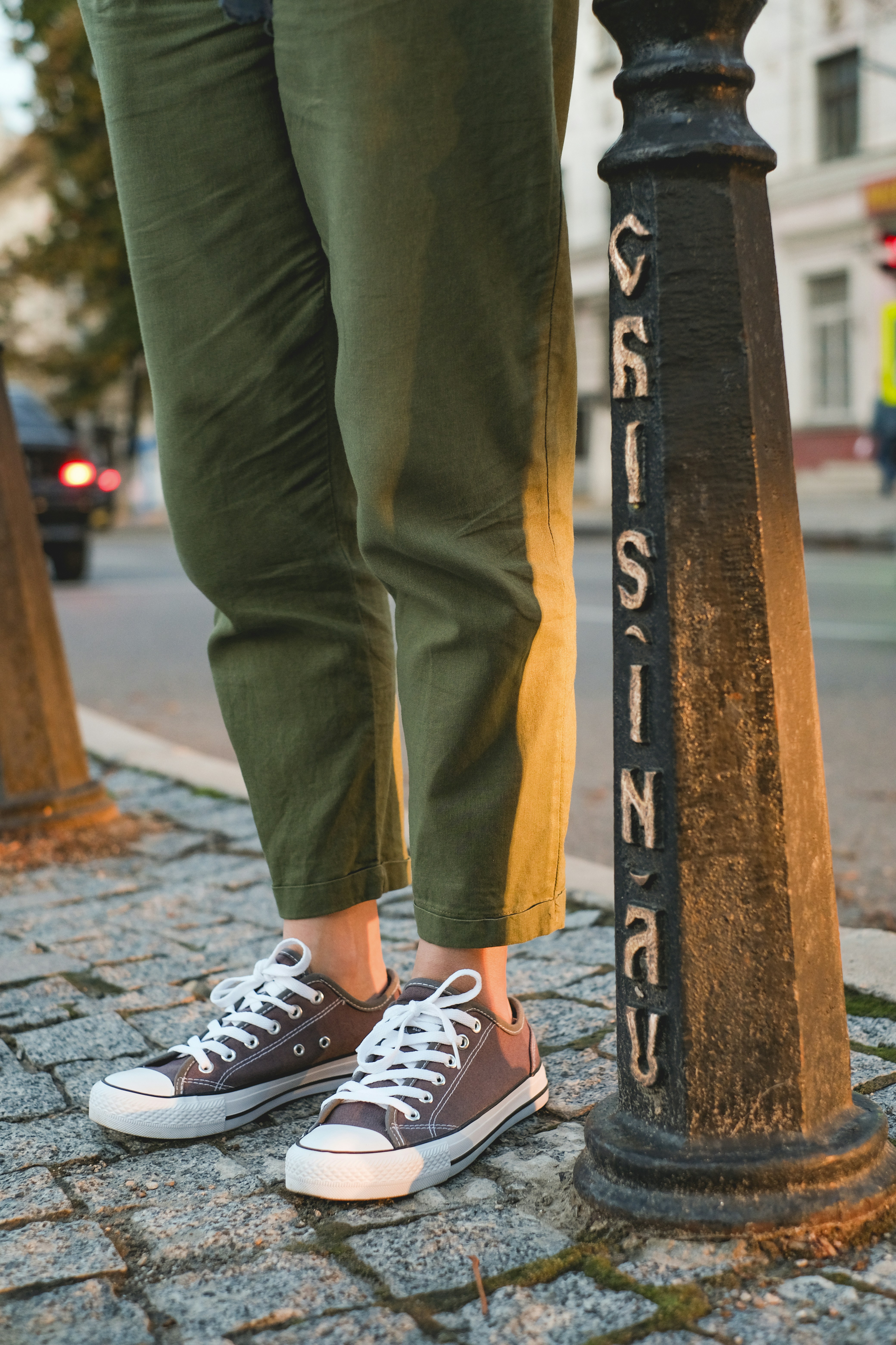 person in gray pants and white and black sneakers standing on black metal bar