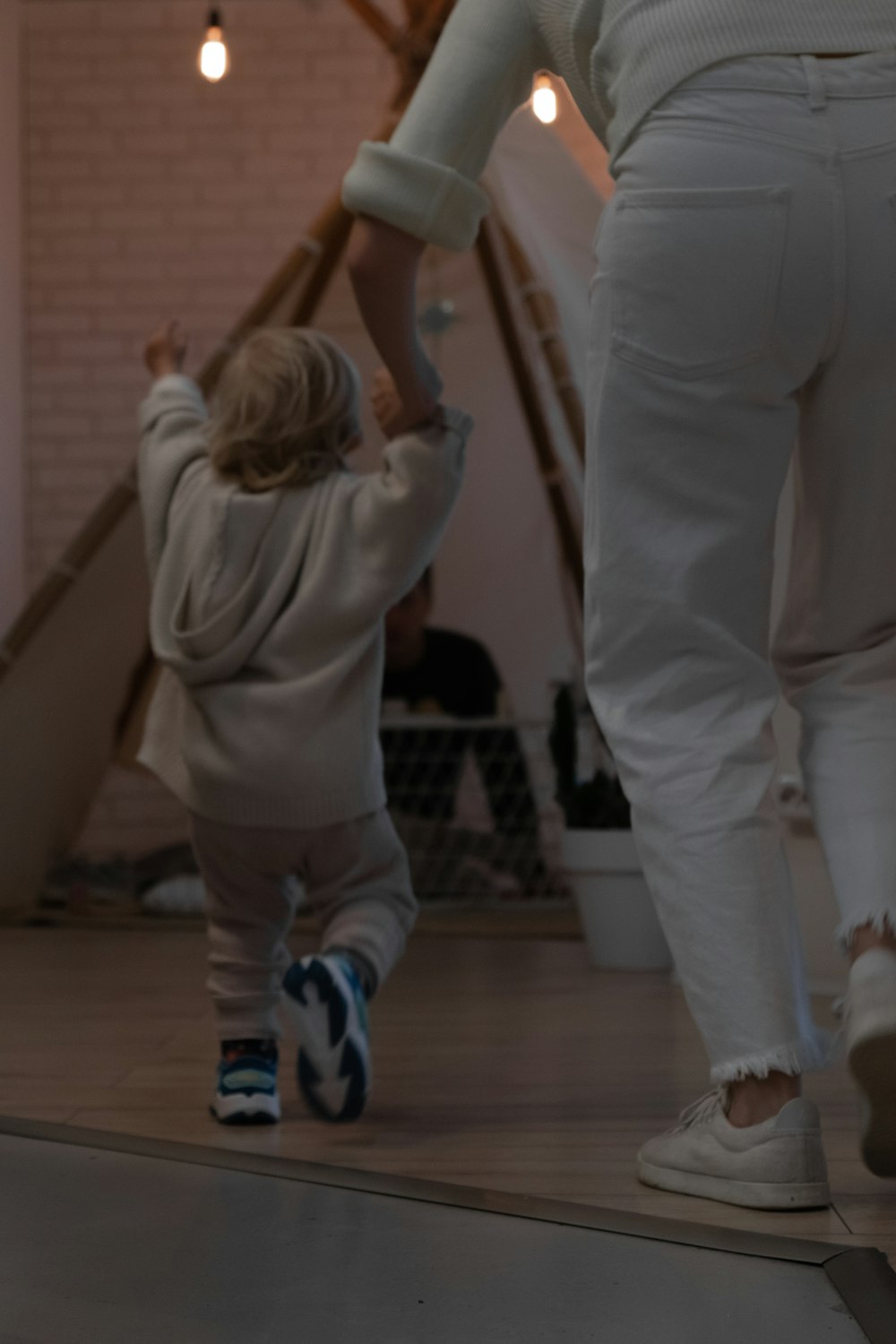 girl in white long sleeve shirt and blue pants standing on brown wooden floor