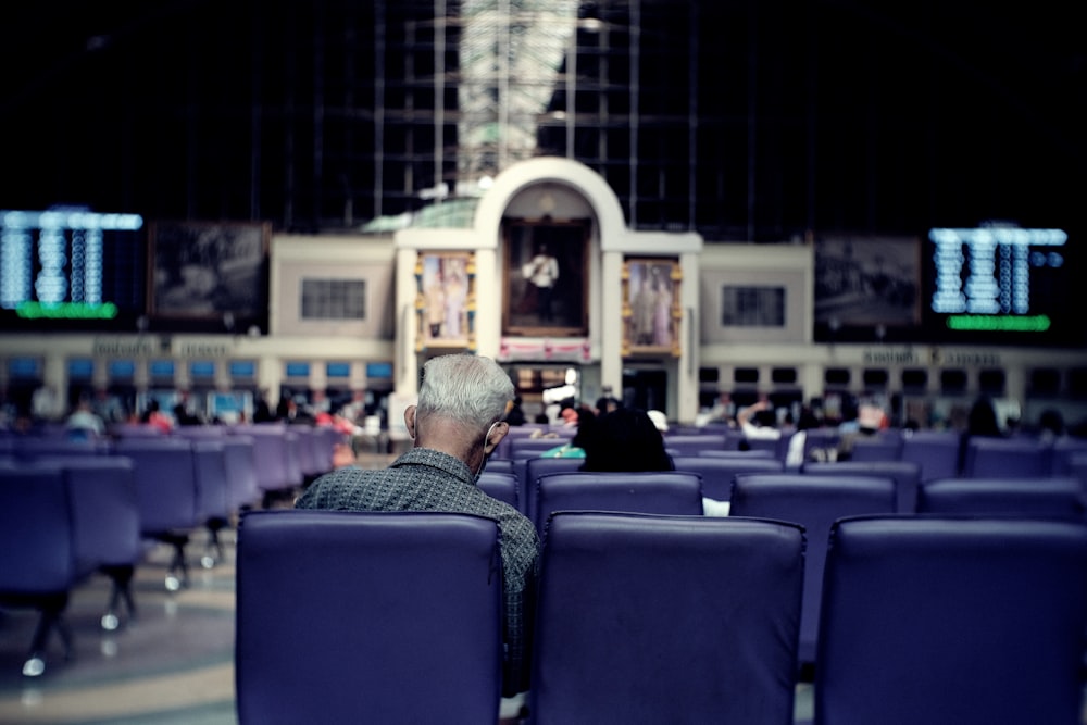 man in black jacket sitting on blue chair