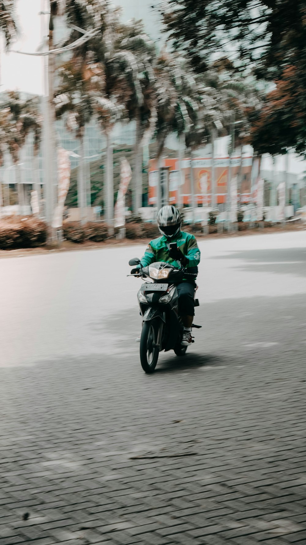 昼間の道路でバイクに乗る緑色のヘルメットをかぶった男