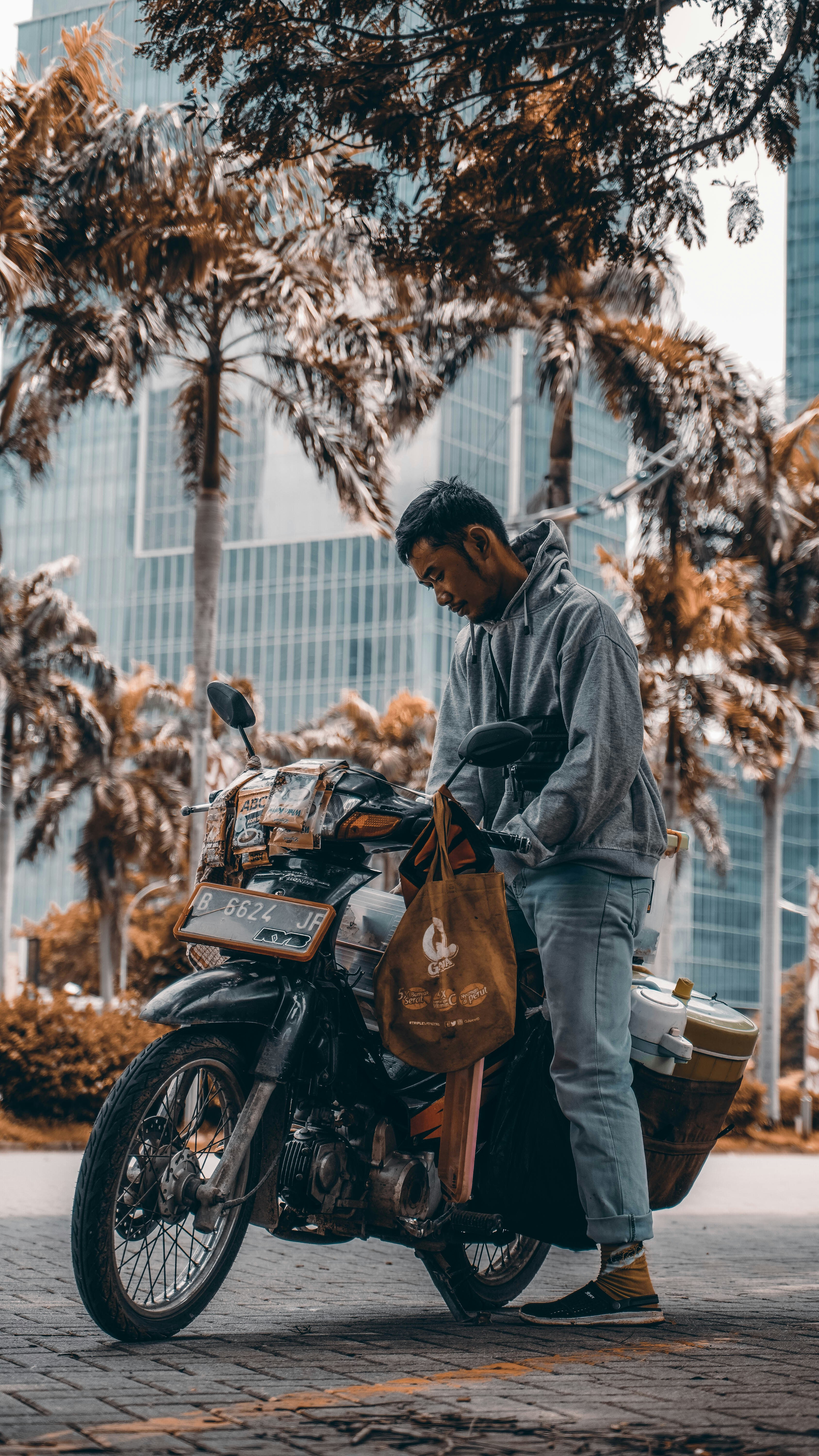 man in black leather jacket and brown pants standing beside black motorcycle during daytime