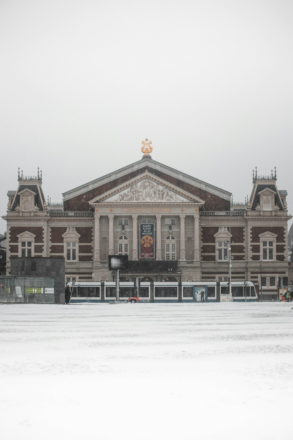 Menschen, die tagsüber auf einem schneebedeckten Feld in der Nähe eines braunen und weißen Betongebäudes spazieren gehen