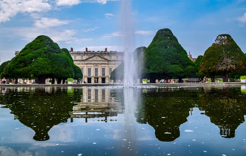 Fuente de agua cerca de árboles verdes y edificio de hormigón marrón durante el día