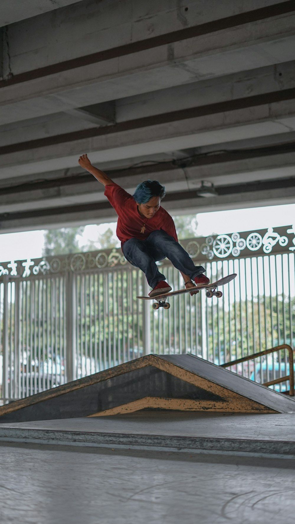 man in red long sleeve shirt and blue denim jeans jumping on brown wooden staircase