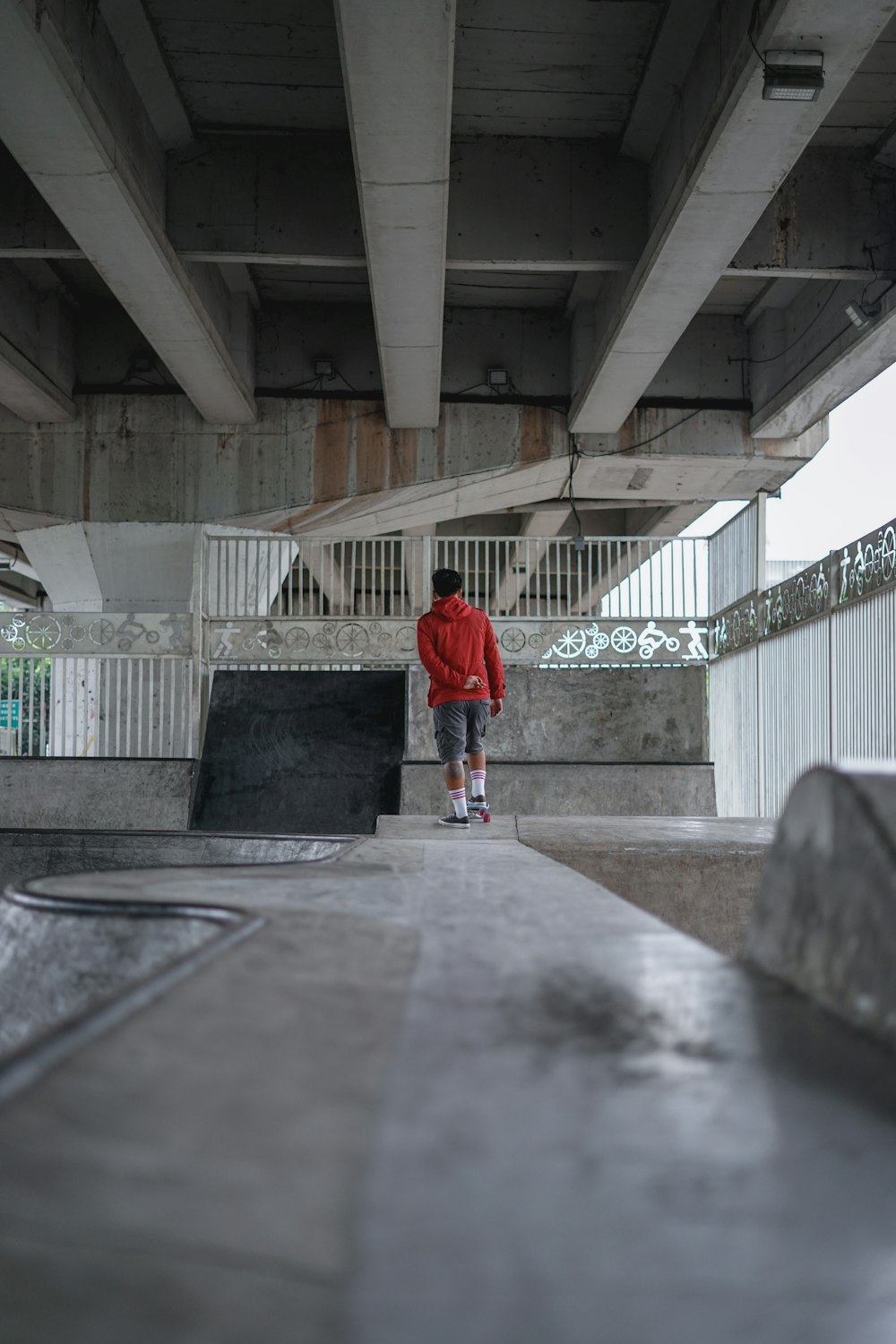 man in red t-shirt and gray pants walking on gray concrete pavement