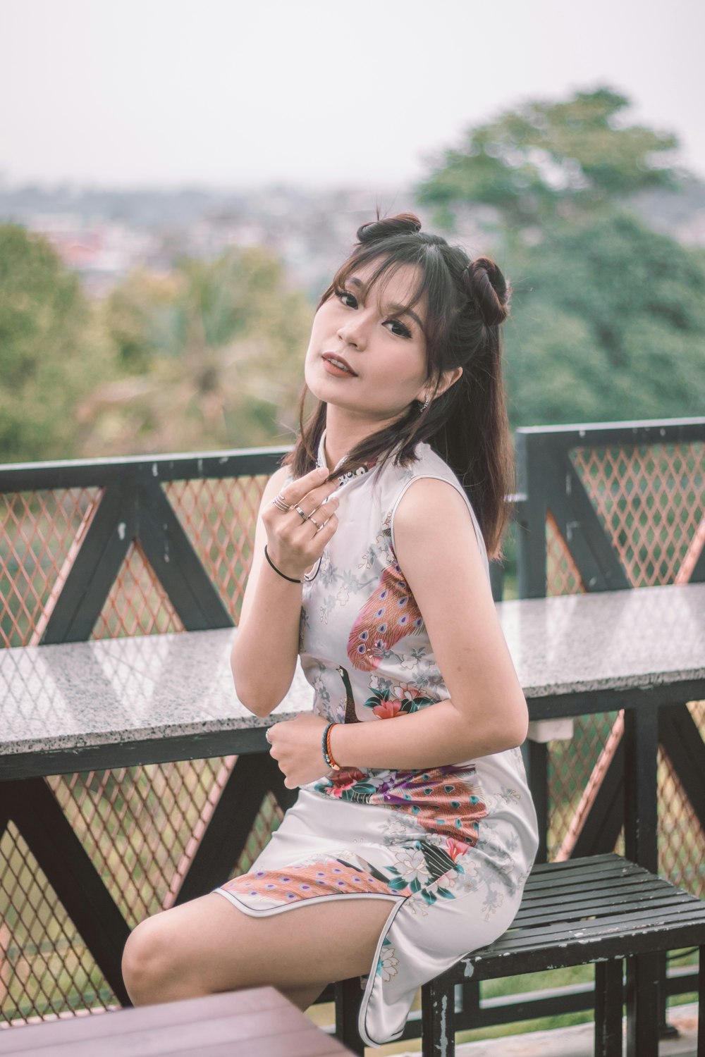 woman in white and orange sleeveless dress sitting on brown wooden bench during daytime