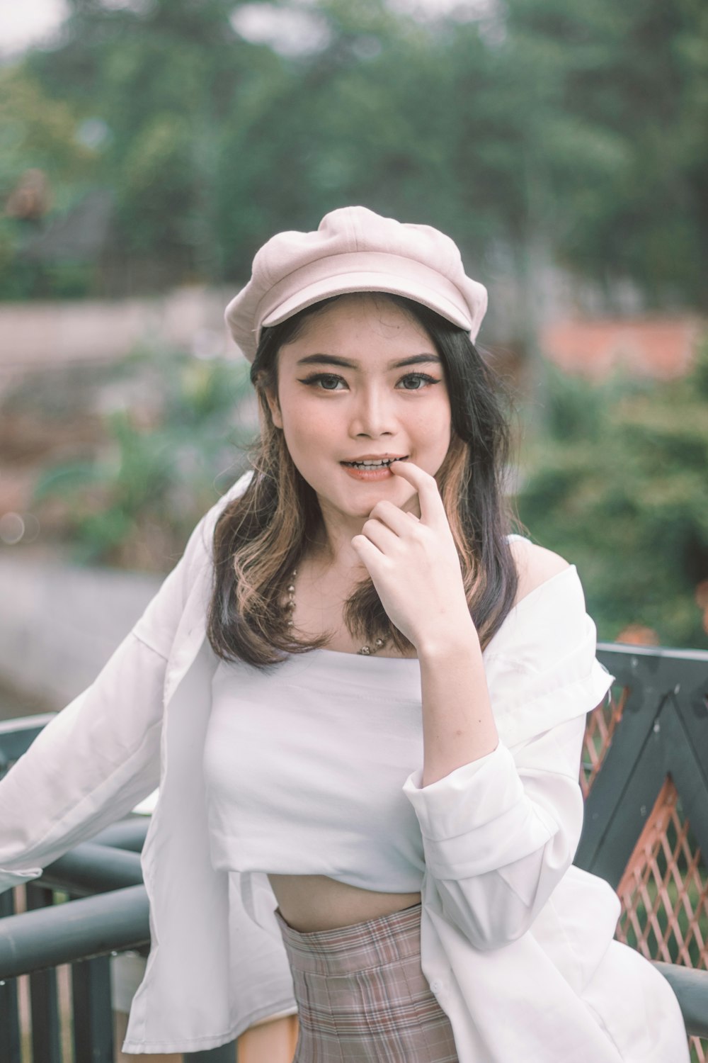 woman in white long sleeve shirt and brown hat sitting on black metal bench during daytime