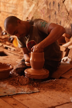 boy in gray and white stripe t-shirt making clay pot